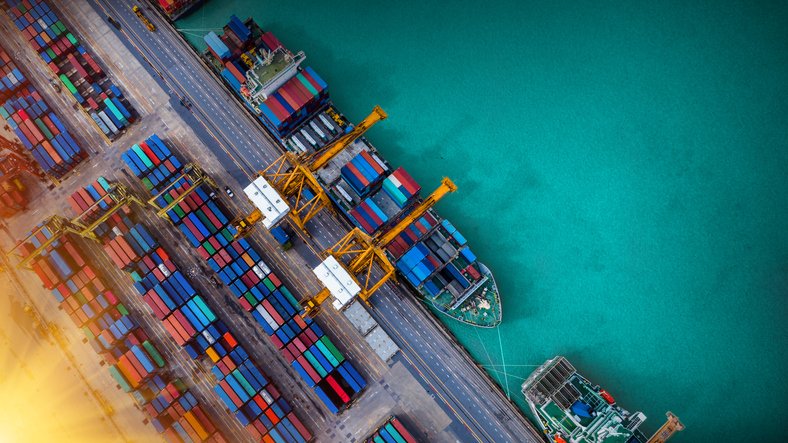 Logistics and transportation of Container Cargo ship and Cargo plane with working crane bridge in shipyard at sunrise, logistic import export and transport industry background